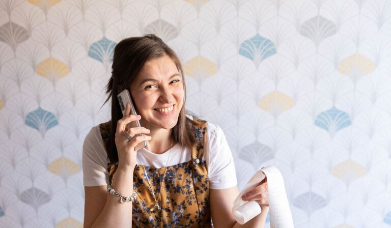La foto di Roberta Targa sorridente con in mano telefono e una fila di conti.