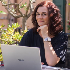 Foto in primo piano di Fulvia Silvestri, donna con capelli scuri e mossi, mano sotto il mento e viso disteso