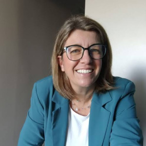 Foto in primo piano di Raffaela Rittore, donna sorridente con capelli a caschetto lungo e giacca verde smeraldo