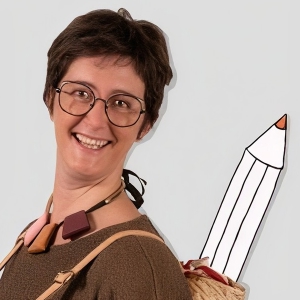 Primo piano di donna con capelli scuri e corti, occhiali, sorridente. Alla sua destra una matita disegnata stile scketch.